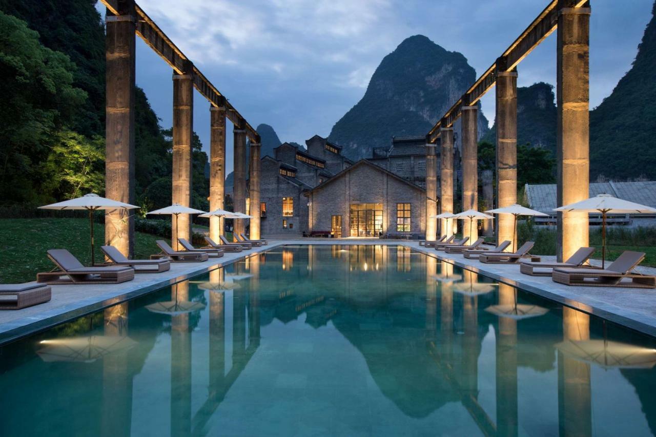 Exterior view of Yangshuo Sugar House resort, showing the preserved 1960s sugar mill architecture against Karst mountains