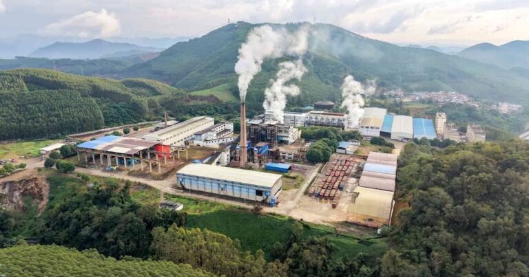 Aerial view of a sugarcane processing mill surrounded by green mountains in Guangxi, China